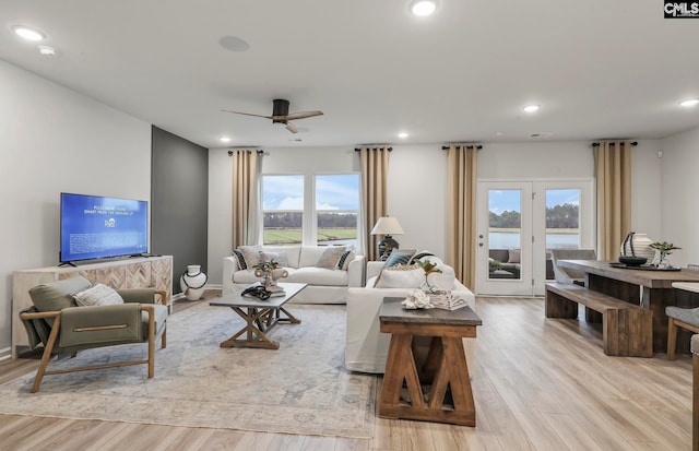 living room featuring ceiling fan, light hardwood / wood-style floors, and plenty of natural light