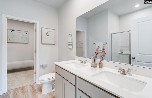 bathroom with toilet, a shower with shower door, hardwood / wood-style floors, and vanity