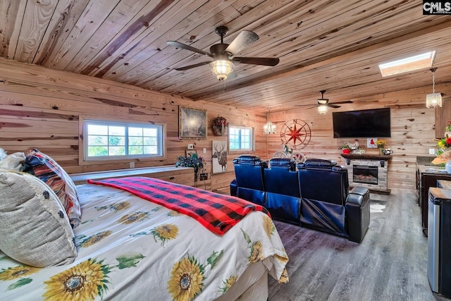 bedroom featuring a stone fireplace, wood walls, hardwood / wood-style floors, and wood ceiling