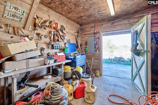 miscellaneous room with electric panel, wooden walls, and a workshop area