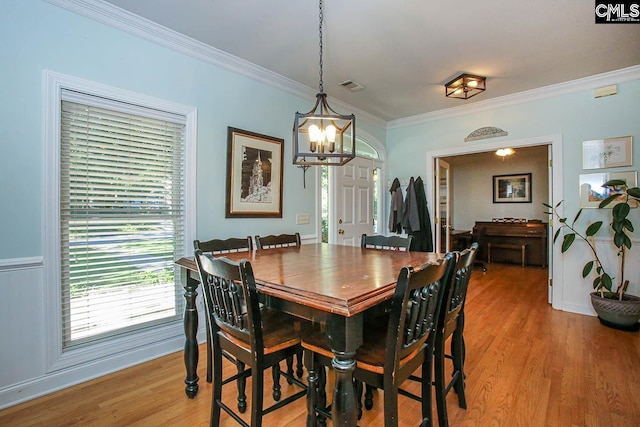 dining area with ornamental molding, a chandelier, and light hardwood / wood-style flooring