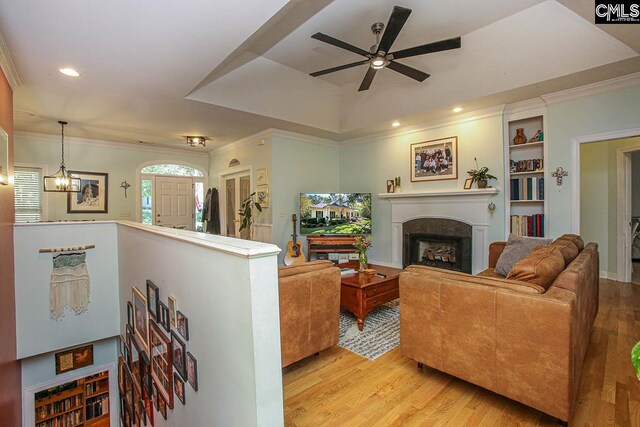 living room with ceiling fan with notable chandelier, light wood-type flooring, and crown molding