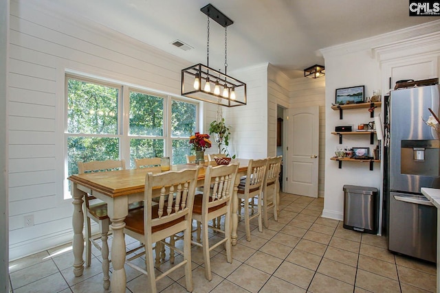 tiled dining space featuring ornamental molding and wood walls