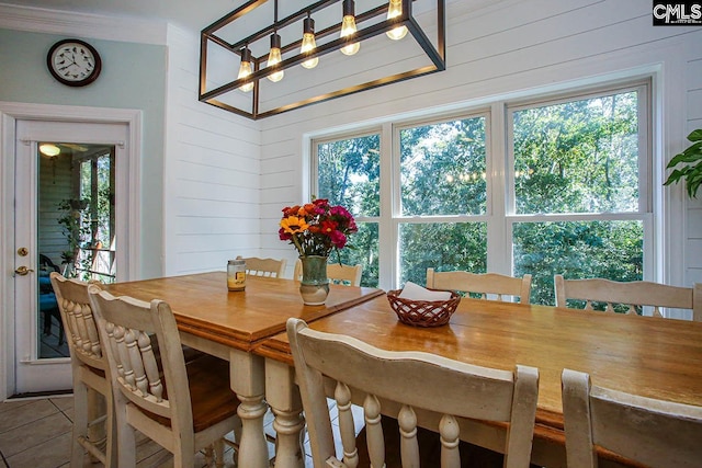 dining area featuring wooden walls, a wealth of natural light, and tile patterned floors