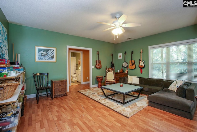 living room featuring ceiling fan, a textured ceiling, and light hardwood / wood-style flooring