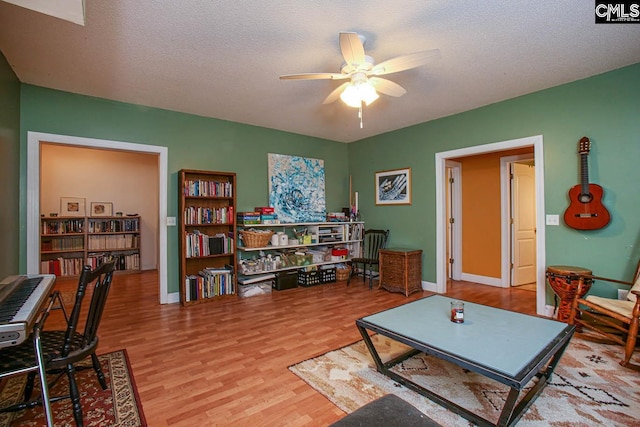 living room featuring hardwood / wood-style flooring, a textured ceiling, and ceiling fan