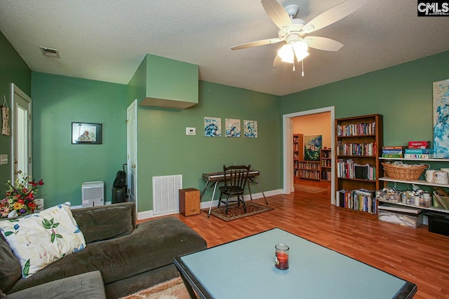 living room with ceiling fan, wood-type flooring, and a textured ceiling