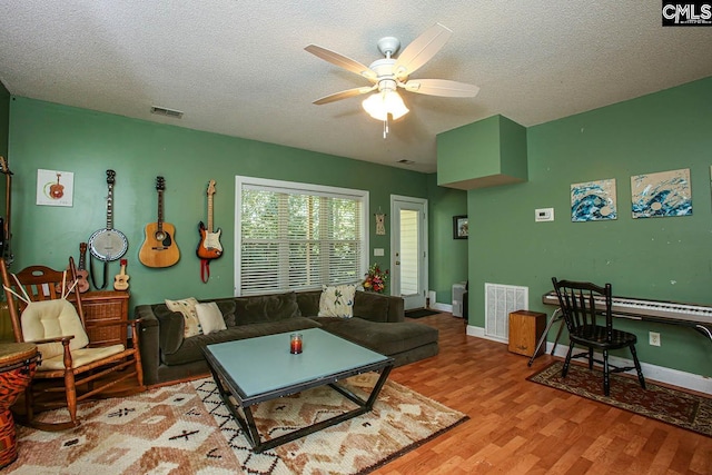 living room featuring light hardwood / wood-style floors, a textured ceiling, and ceiling fan