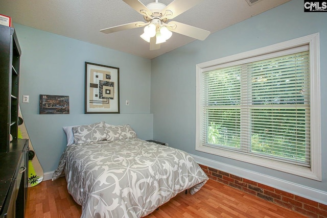 bedroom featuring ceiling fan, a textured ceiling, and wood-type flooring