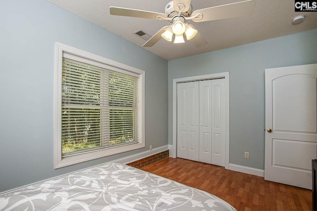 bedroom featuring wood-type flooring, a closet, a textured ceiling, and ceiling fan