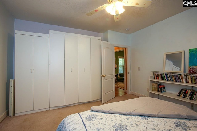 bedroom with light carpet, a textured ceiling, a closet, and ceiling fan