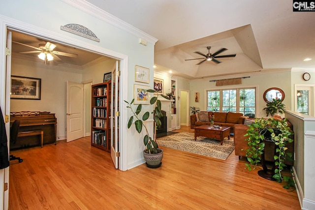 living room with light hardwood / wood-style floors, ornamental molding, and ceiling fan