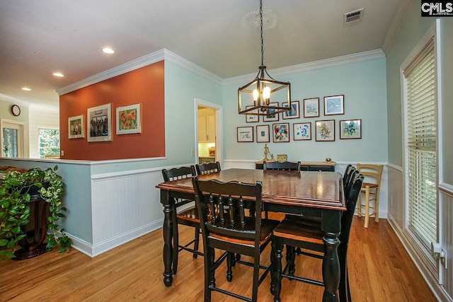 dining space with crown molding, a chandelier, and light wood-type flooring