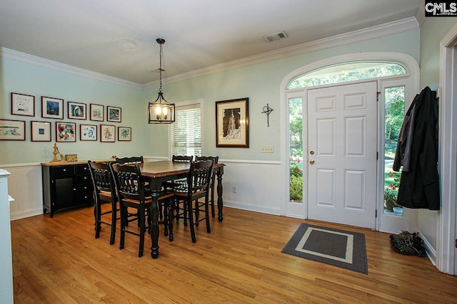 dining area with plenty of natural light, crown molding, and light wood-type flooring