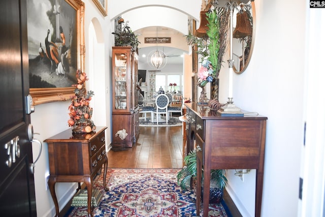 hall featuring dark wood-type flooring and a chandelier