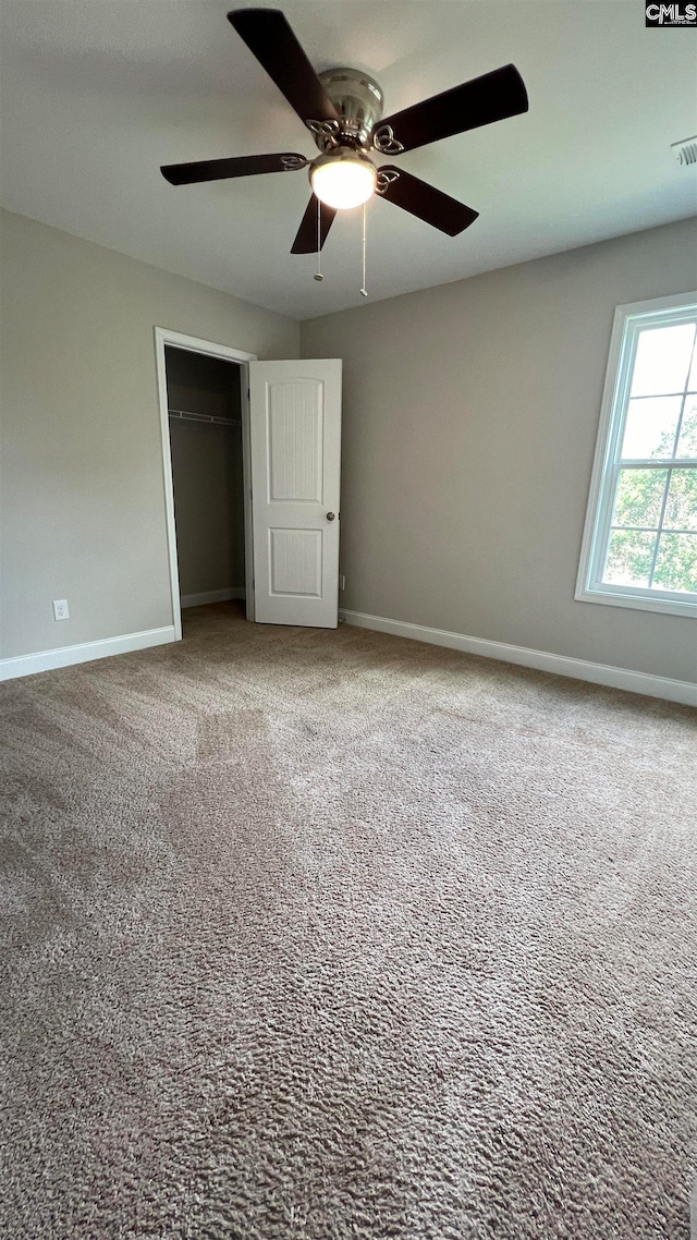 unfurnished bedroom with ceiling fan, a closet, and carpet flooring