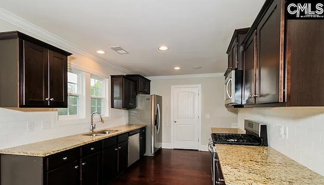 kitchen with light stone counters, sink, backsplash, dark wood-type flooring, and stainless steel appliances