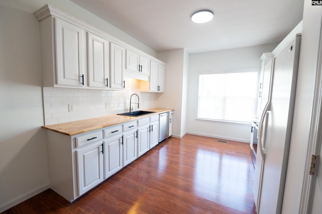 kitchen with white cabinets, butcher block counters, sink, and dishwasher