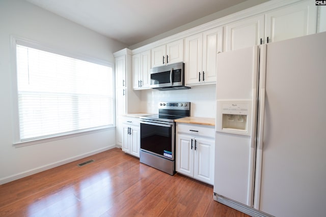 kitchen featuring appliances with stainless steel finishes, decorative backsplash, white cabinetry, and wood-type flooring