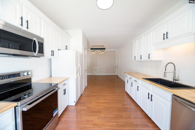 kitchen featuring white cabinets, light wood-type flooring, sink, stainless steel appliances, and butcher block countertops