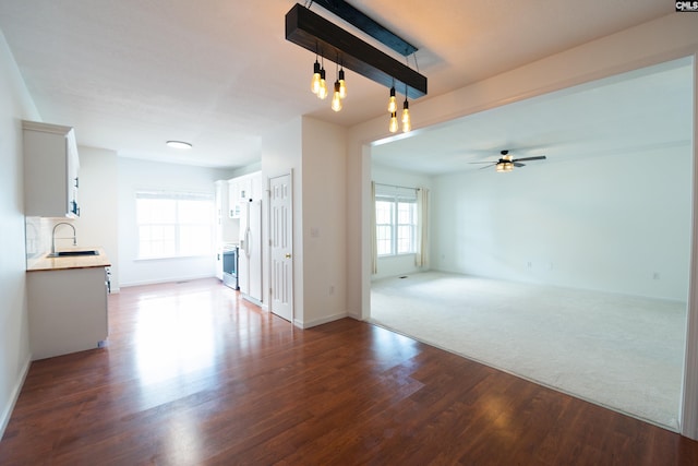 unfurnished room with a healthy amount of sunlight, sink, wood-type flooring, and ceiling fan