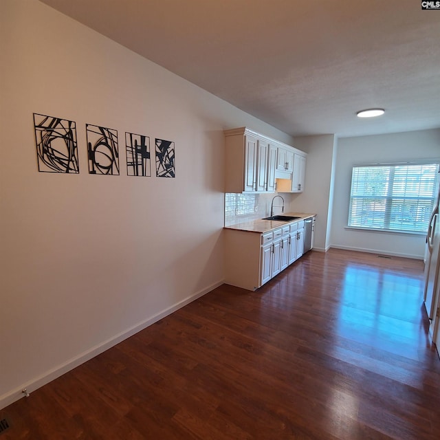 kitchen with sink, stainless steel dishwasher, white cabinets, decorative backsplash, and dark hardwood / wood-style floors