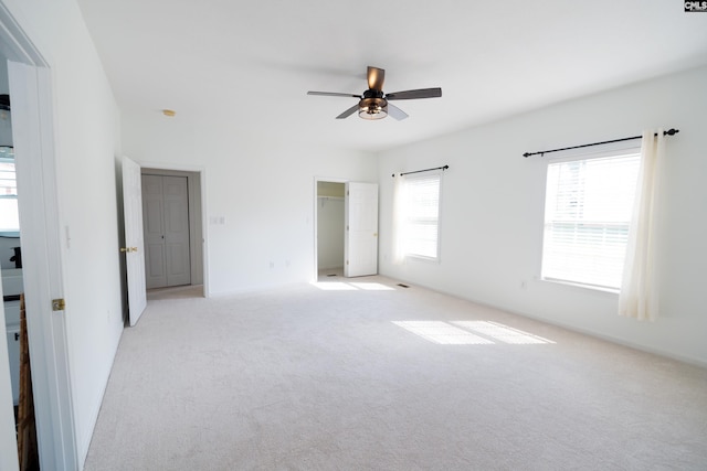 unfurnished room with ceiling fan, a wealth of natural light, and light colored carpet