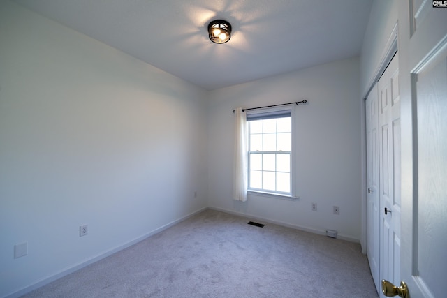 unfurnished bedroom with light carpet and a closet