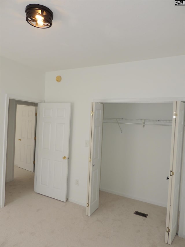 unfurnished bedroom featuring a closet and light colored carpet