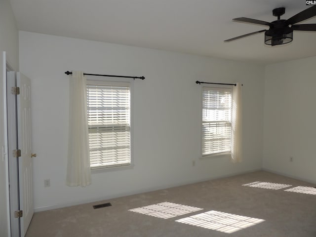 carpeted empty room featuring ceiling fan and plenty of natural light