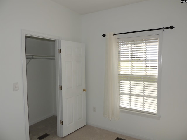 unfurnished bedroom with light carpet and a closet