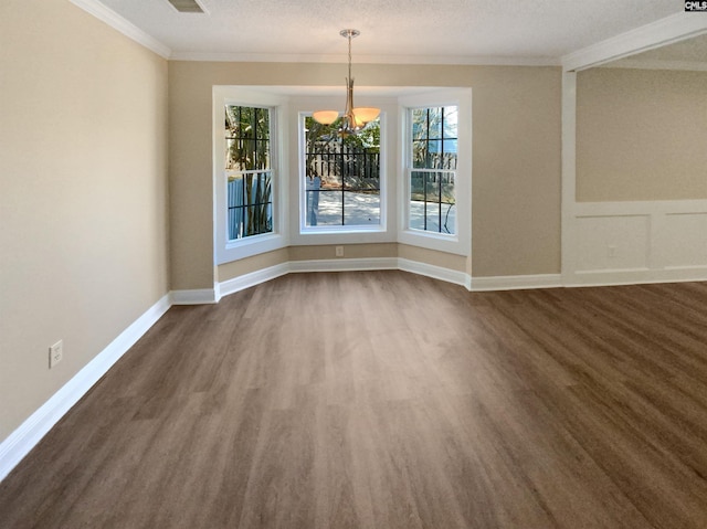 unfurnished dining area featuring dark wood-type flooring, crown molding, a notable chandelier, and a textured ceiling