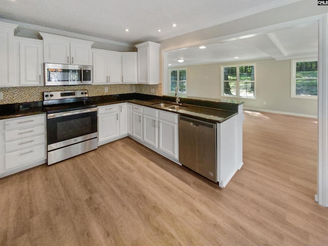 kitchen with sink, light wood-type flooring, white cabinetry, appliances with stainless steel finishes, and tasteful backsplash