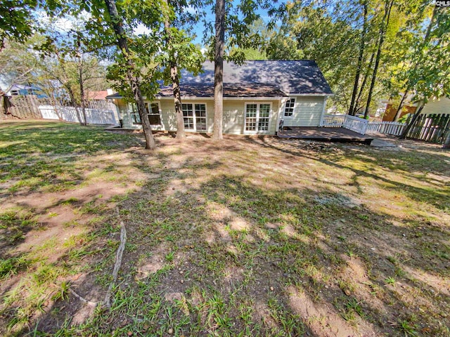 rear view of house featuring a wooden deck and a lawn