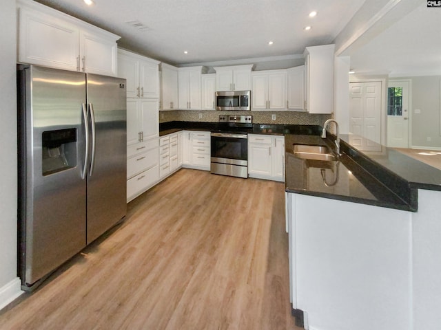 kitchen featuring appliances with stainless steel finishes, sink, kitchen peninsula, and white cabinets