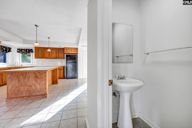 bathroom featuring tasteful backsplash, a textured ceiling, sink, and tile patterned flooring