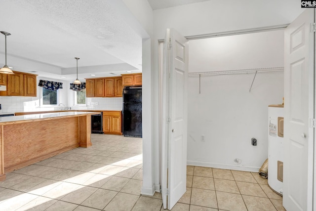 kitchen with black refrigerator, pendant lighting, backsplash, and light tile patterned floors