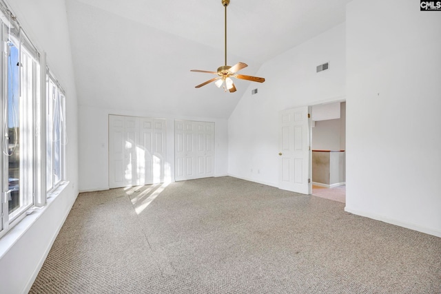 empty room with high vaulted ceiling, carpet flooring, and a wealth of natural light