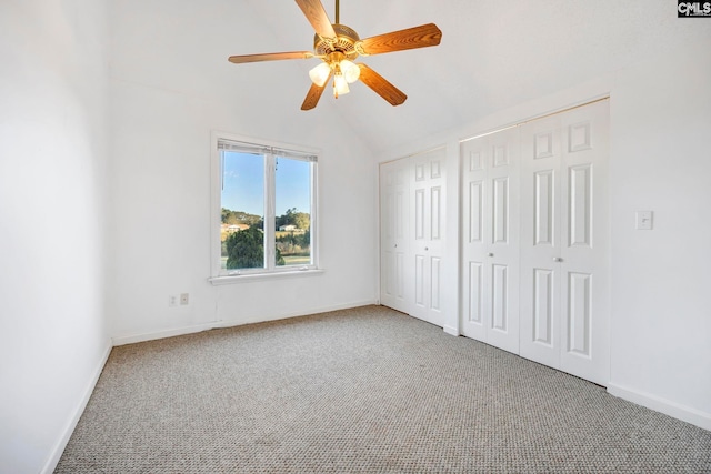 unfurnished bedroom with lofted ceiling, multiple closets, carpet flooring, and ceiling fan