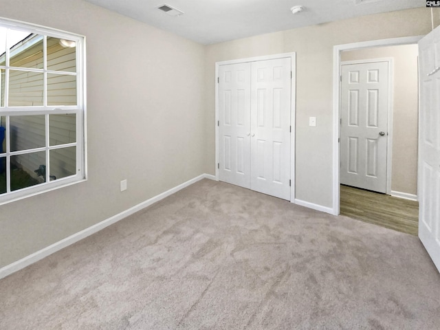 unfurnished bedroom with light carpet and a closet