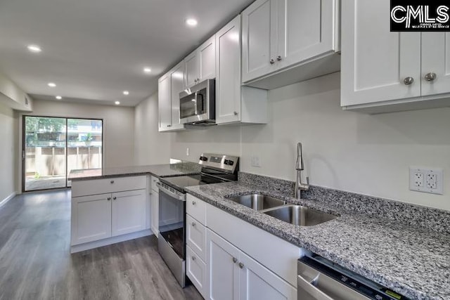 kitchen featuring hardwood / wood-style floors, white cabinets, light stone countertops, sink, and stainless steel appliances