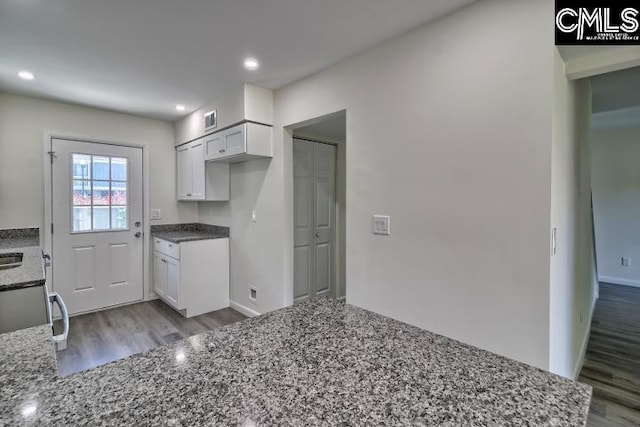 kitchen with stone counters, white cabinets, and hardwood / wood-style flooring