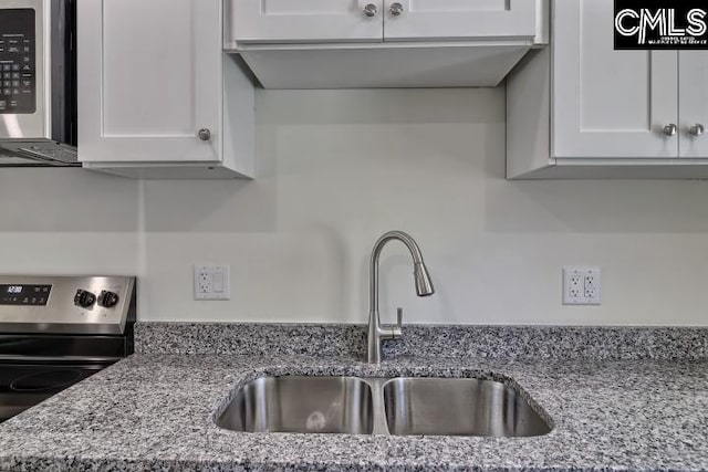 kitchen with white cabinetry, light stone counters, stainless steel appliances, and sink