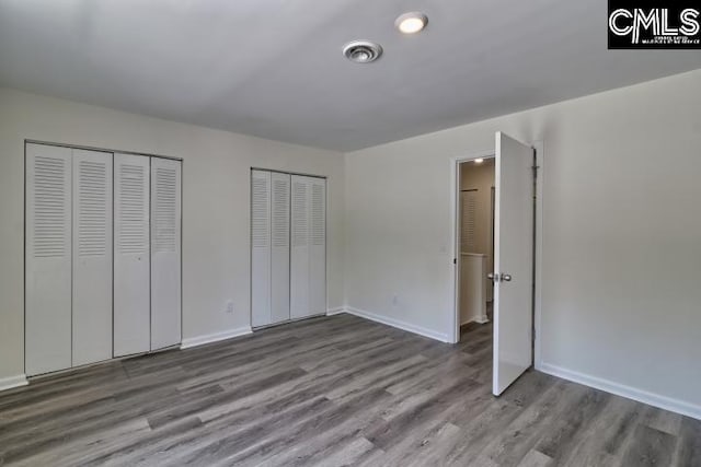 unfurnished bedroom featuring multiple closets and light wood-type flooring