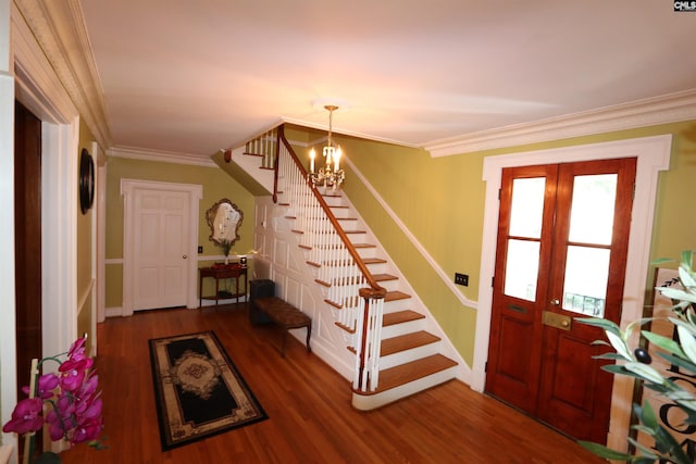 foyer entrance with crown molding, dark hardwood / wood-style floors, a notable chandelier, and french doors