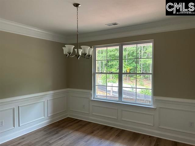 unfurnished dining area with hardwood / wood-style flooring, ornamental molding, and a chandelier