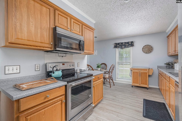 kitchen with a textured ceiling, light wood-type flooring, and stainless steel appliances