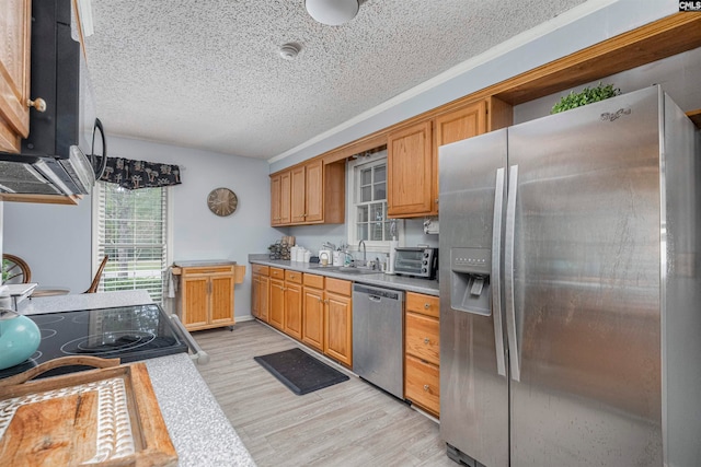 kitchen with a textured ceiling, stainless steel appliances, light hardwood / wood-style floors, and sink