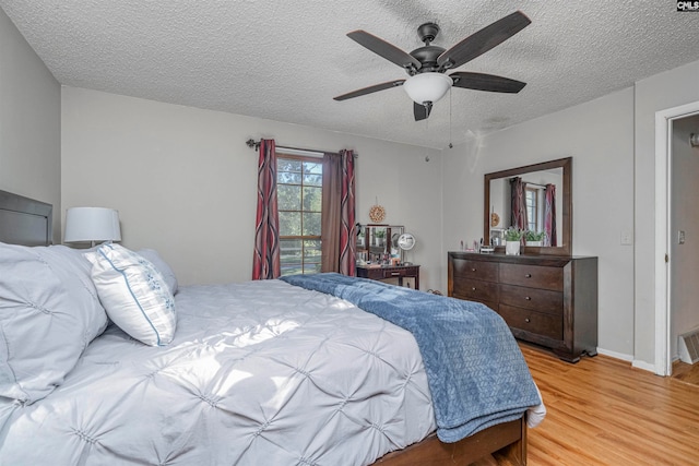 bedroom with ceiling fan, wood-type flooring, and a textured ceiling