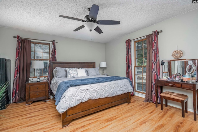 bedroom featuring ceiling fan, light wood-type flooring, and a textured ceiling